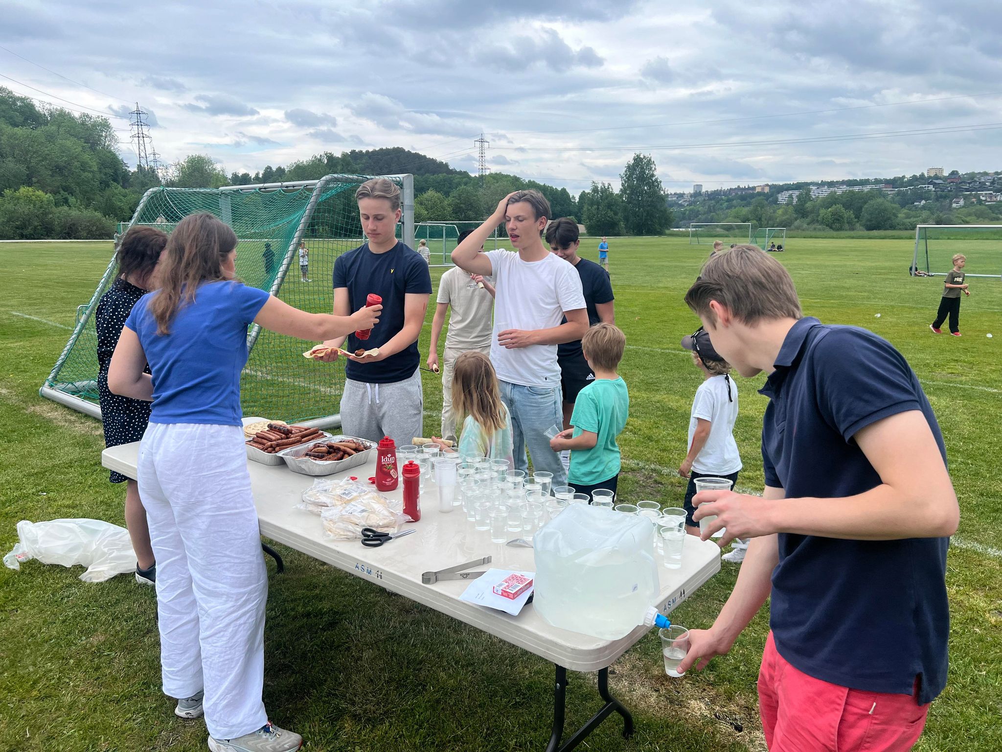 en gruppe mennesker som står rundt et bord med mat på