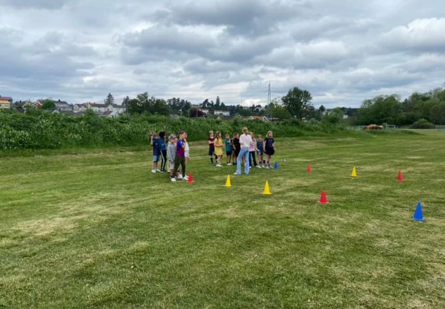 En gruppe mennesker som står på en gresslette med kjegler og overskyet himmel