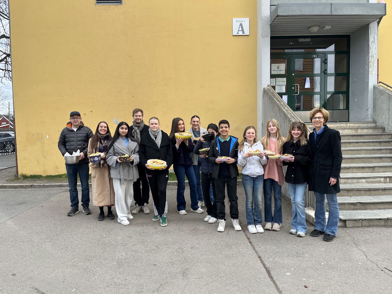 en gruppe mennesker som poserer for et bilde utenfor en bygning