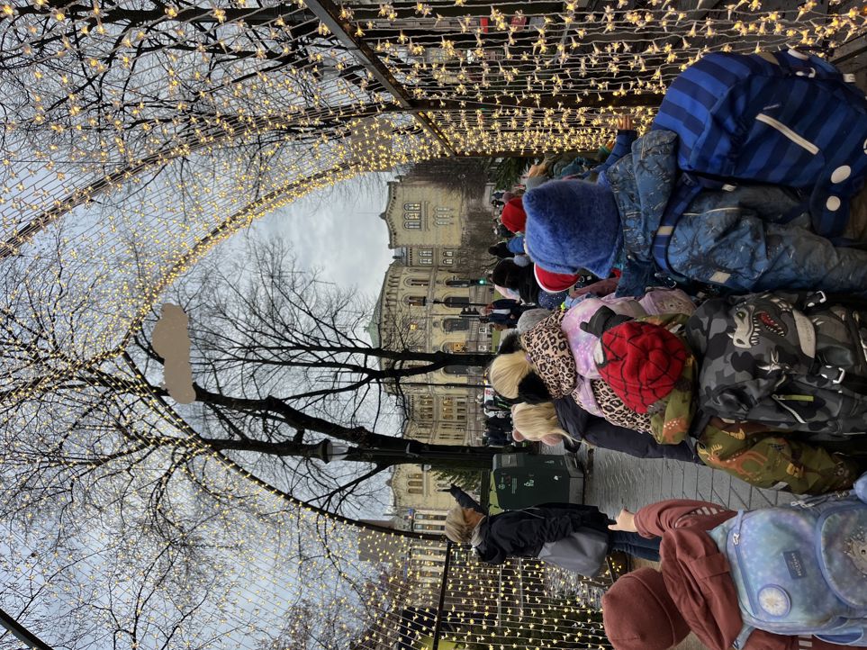 en gruppe mennesker som står på fortauet med et tre i bakgrunnen