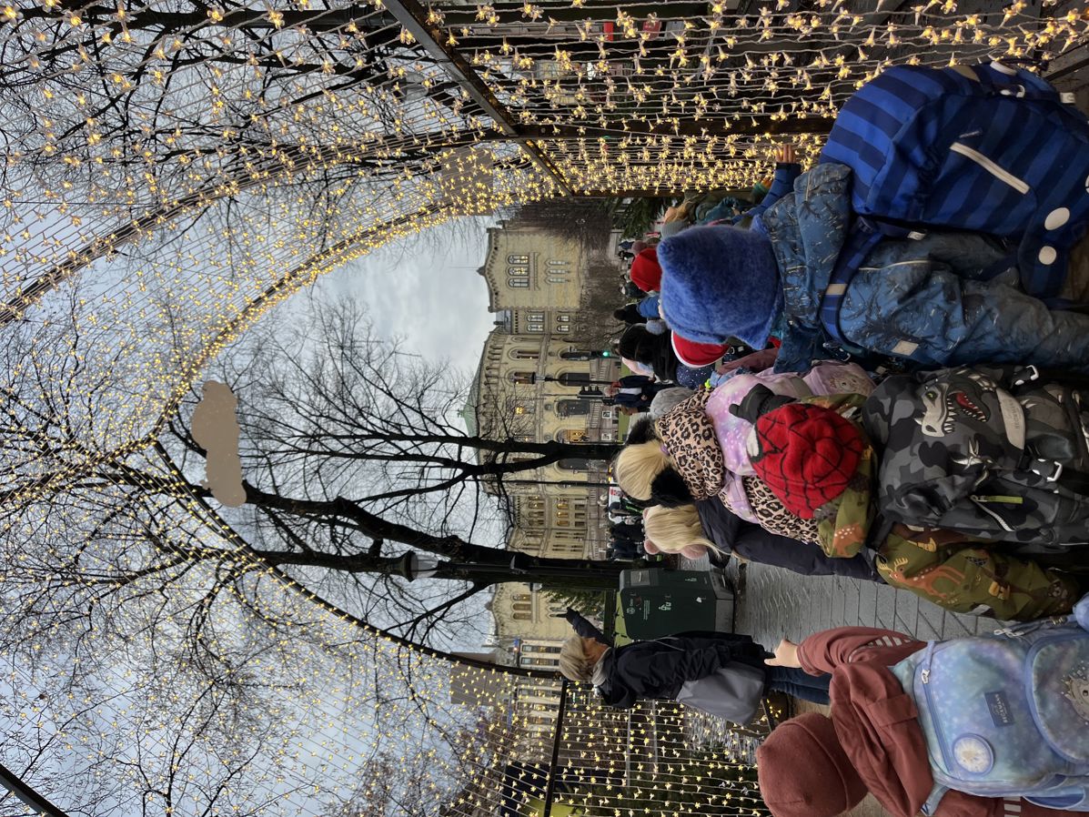 en gruppe mennesker som står på fortauet med et tre i bakgrunnen