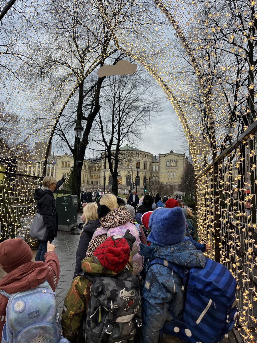 en gruppe mennesker som står på fortauet med et tre i bakgrunnen