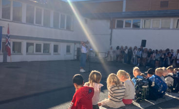 en gruppe mennesker som sitter på en benk foran en bygning