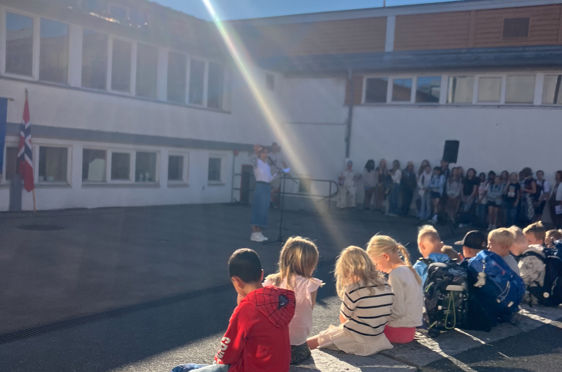 en gruppe mennesker som sitter på en benk foran en bygning