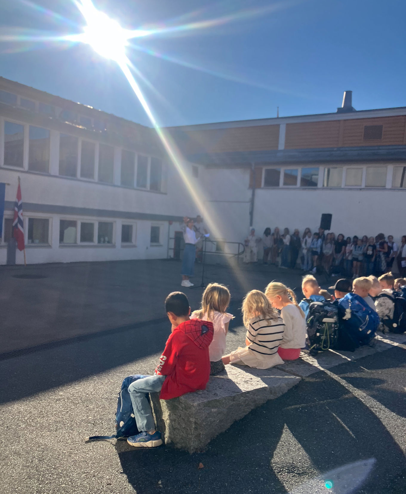 en gruppe mennesker som sitter på en benk foran en bygning